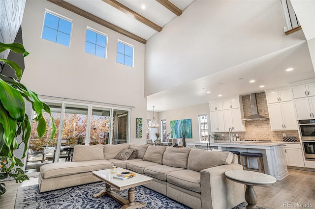 living room with beamed ceiling, plenty of natural light, light hardwood / wood-style flooring, and high vaulted ceiling