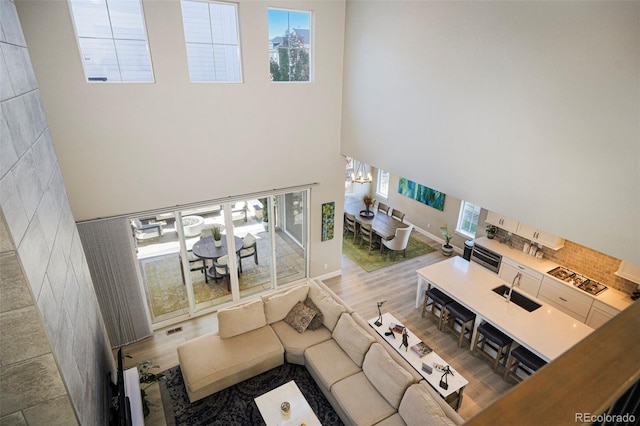 living room featuring a high ceiling, an inviting chandelier, and light hardwood / wood-style flooring