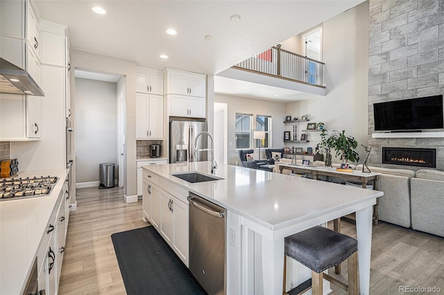 kitchen with a breakfast bar area, sink, a kitchen island with sink, and light hardwood / wood-style flooring