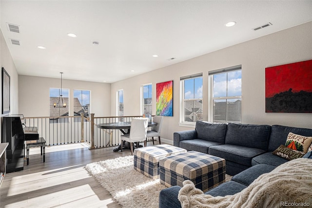 living room featuring light hardwood / wood-style flooring, a chandelier, and plenty of natural light