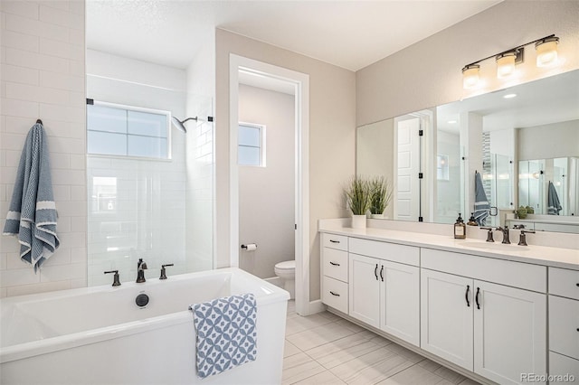 bathroom with tile patterned flooring, a washtub, vanity, and toilet