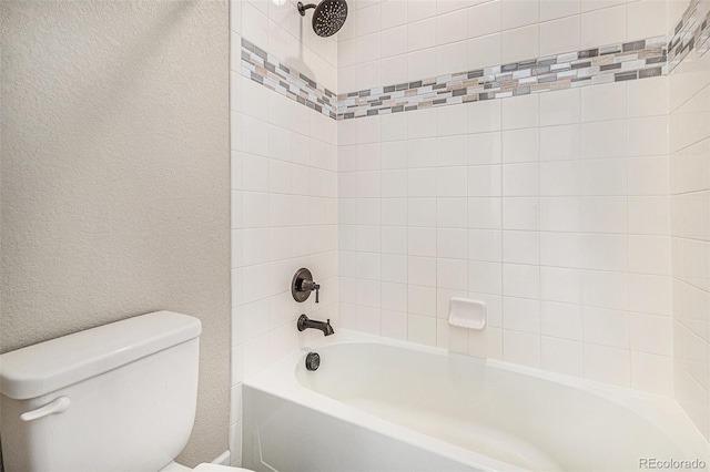 bathroom featuring tiled shower / bath combo and toilet