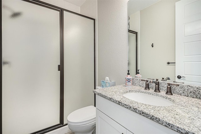 bathroom with toilet, vanity, and a shower with door