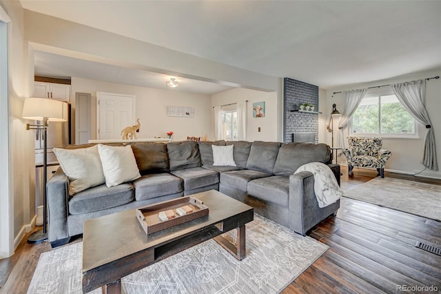 living room featuring a brick fireplace and hardwood / wood-style floors