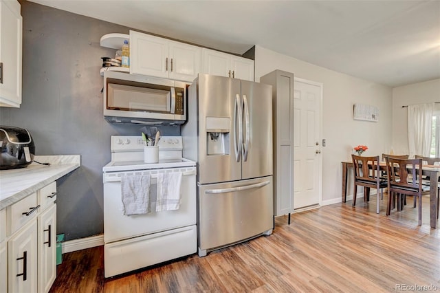 kitchen with light stone countertops, light hardwood / wood-style flooring, stainless steel appliances, and white cabinets