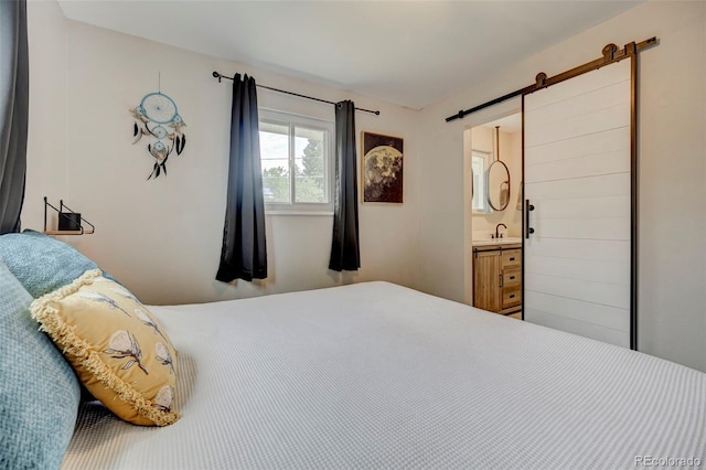 bedroom featuring ensuite bathroom and a barn door