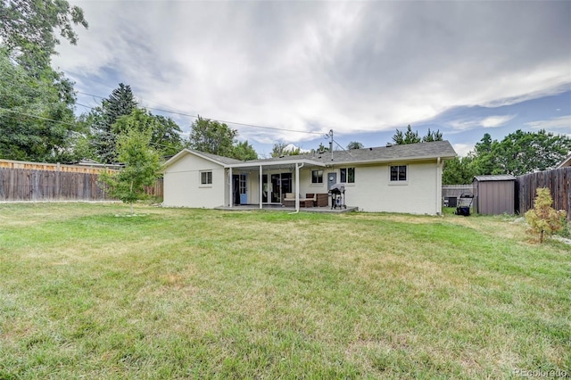 back of property featuring a lawn, a storage unit, and a patio area