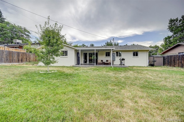 back of property with a storage shed, a yard, and a patio area