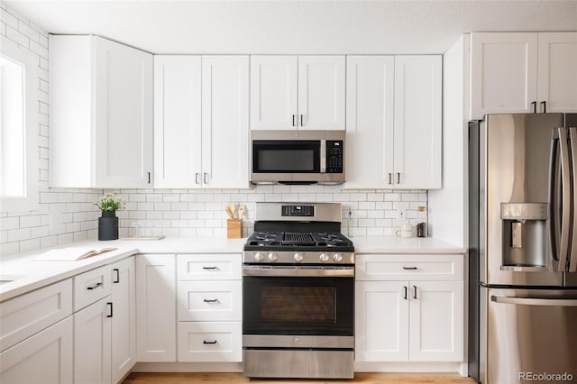 kitchen featuring appliances with stainless steel finishes, decorative backsplash, white cabinets, and light hardwood / wood-style flooring