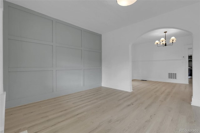 2803 N Cascade Ave, Colorado Springs, CO 80907 - empty room with arched walkways, a decorative wall, a chandelier, and light wood-style flooring