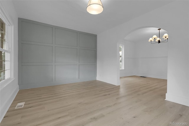 2803 N Cascade Ave, Colorado Springs, CO 80907 - spare room with a decorative wall, arched walkways, a chandelier, plenty of natural light, and light wood-type flooring