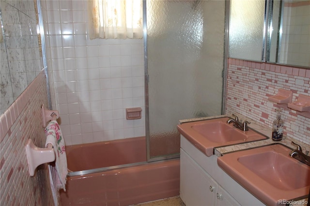 bathroom with backsplash, shower / bath combination with glass door, vanity, and tile walls