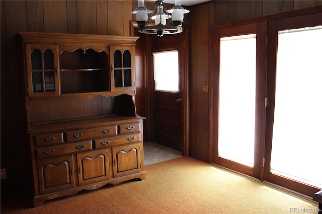 interior space with wooden walls, an inviting chandelier, and plenty of natural light