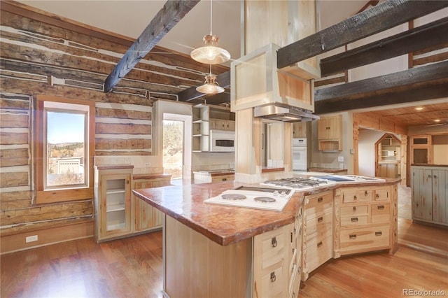 kitchen with beamed ceiling, a center island, white appliances, and light wood-type flooring