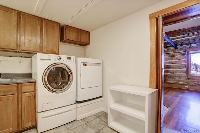 laundry room with cabinets, light hardwood / wood-style floors, washer and clothes dryer, wood walls, and sink