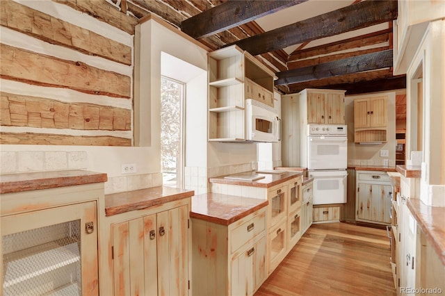 kitchen with white appliances, beam ceiling, and light hardwood / wood-style flooring