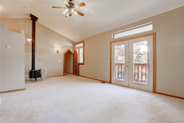 unfurnished room featuring french doors, vaulted ceiling, a wood stove, and carpet floors