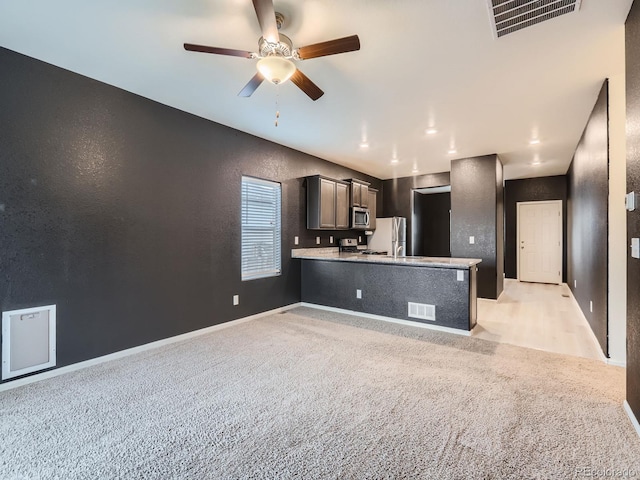 kitchen featuring kitchen peninsula, stainless steel appliances, ceiling fan, and light colored carpet