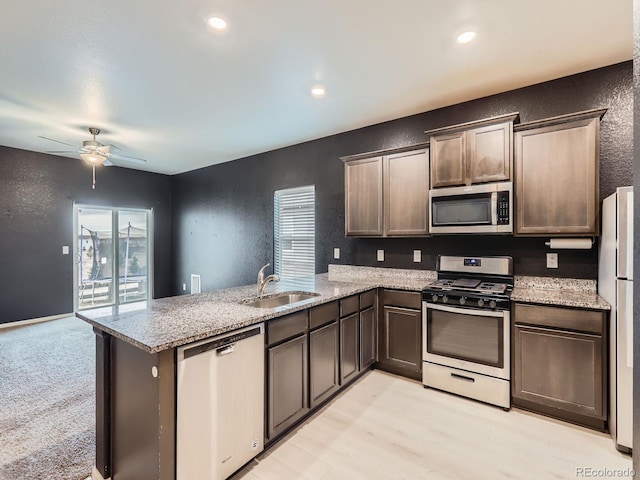 kitchen featuring sink, ceiling fan, appliances with stainless steel finishes, light stone counters, and kitchen peninsula