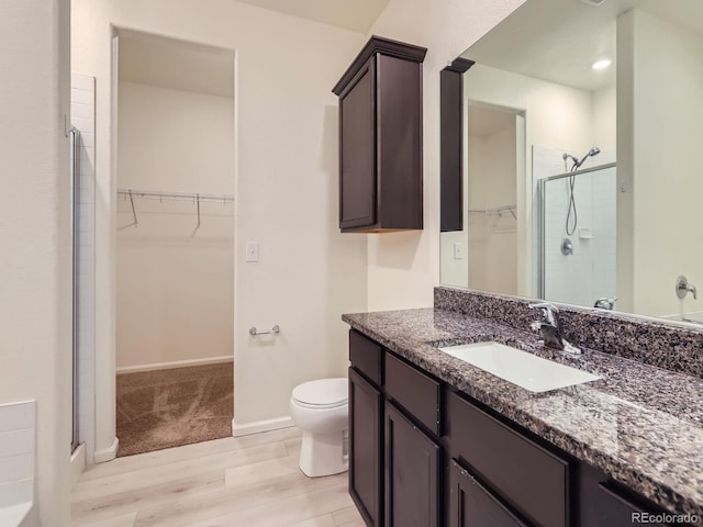 bathroom featuring hardwood / wood-style flooring, vanity, toilet, and walk in shower