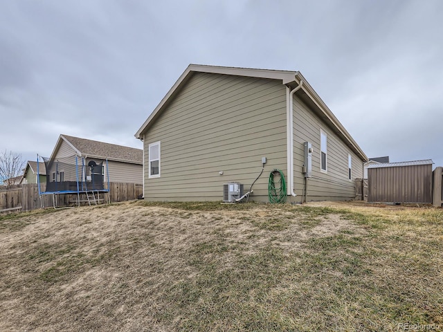 back of house with a trampoline, a shed, and a lawn