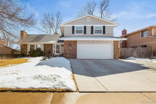 traditional home featuring brick siding, driveway, an attached garage, and fence