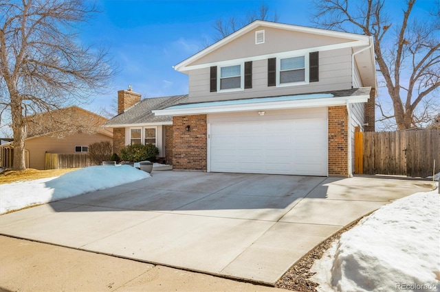 traditional home with driveway, a garage, a chimney, fence, and brick siding