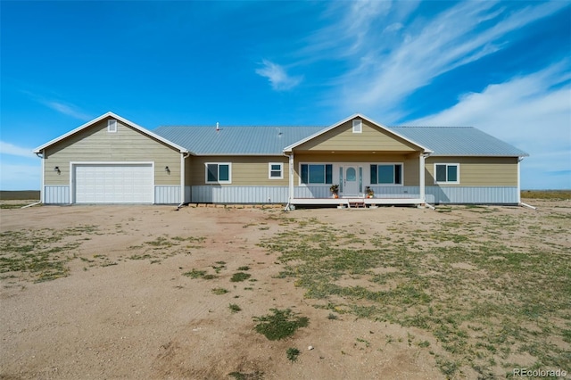 ranch-style home featuring an attached garage, metal roof, and driveway