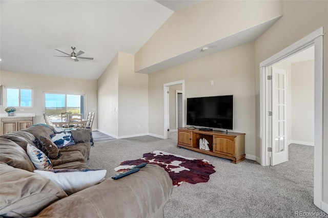 living area featuring light carpet, baseboards, high vaulted ceiling, and a ceiling fan