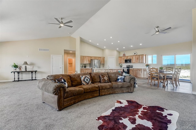 carpeted living room with ceiling fan and high vaulted ceiling