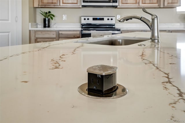 room details featuring white range, light brown cabinets, sink, and light stone counters