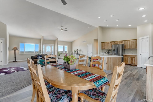 dining space with ceiling fan, light wood-type flooring, and high vaulted ceiling