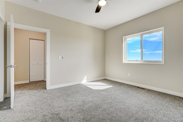 unfurnished room with ceiling fan and carpet