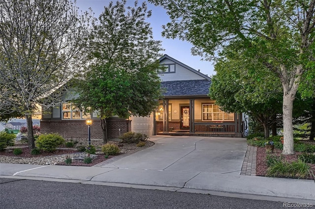 15333 Heritage Cir, Thornton, CO 80602 - view of property hidden behind natural elements featuring brick siding, a porch, concrete driveway, and a garage
