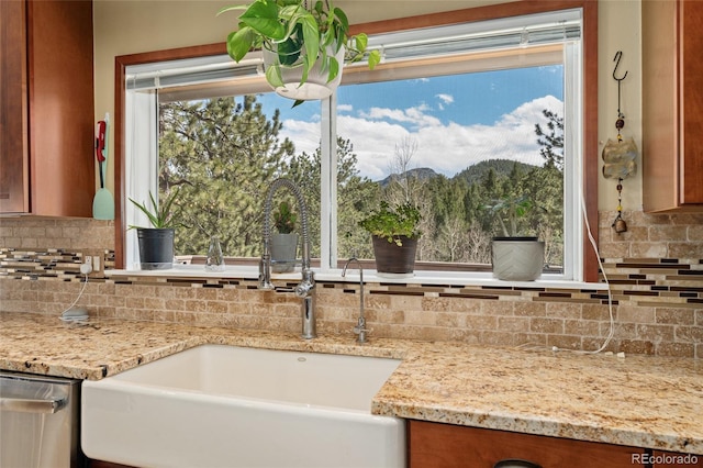 11398 Ranch Elsie Rd, Golden, CO 80403 - kitchen featuring stainless steel dishwasher, light stone counters, a sink, brown cabinets, and backsplash