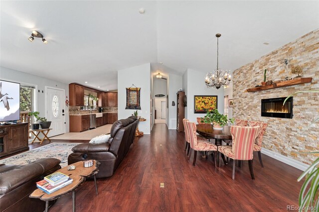 11398 Ranch Elsie Rd, Golden, CO 80403 - living room featuring baseboards, a stone fireplace, wood finished floors, and a notable chandelier