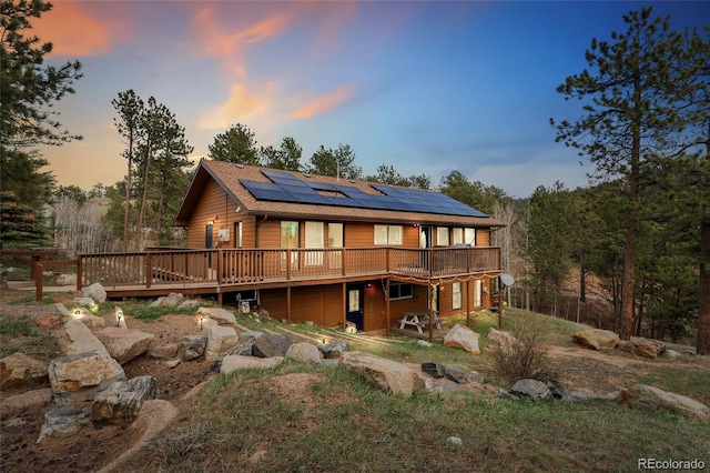 11398 Ranch Elsie Rd, Golden, CO 80403 - back of property at dusk featuring roof mounted solar panels and a wooden deck