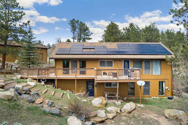11398 Ranch Elsie Rd, Golden, CO 80403 - back of property featuring roof mounted solar panels, a wooden deck, and a shingled roof