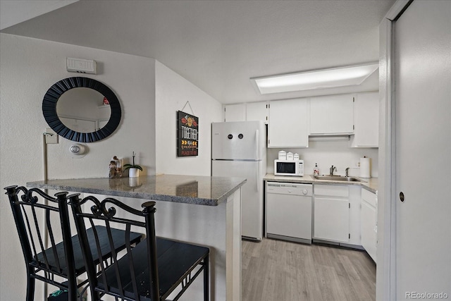 kitchen featuring kitchen peninsula, light hardwood / wood-style floors, white appliances, a breakfast bar area, and white cabinets