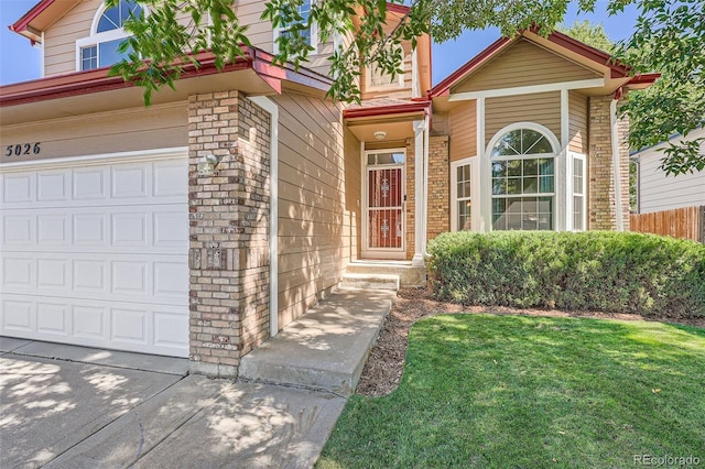 view of exterior entry with a garage and a yard