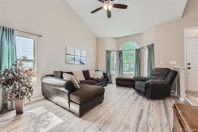 living area with high vaulted ceiling, light wood-type flooring, ceiling fan, and baseboards