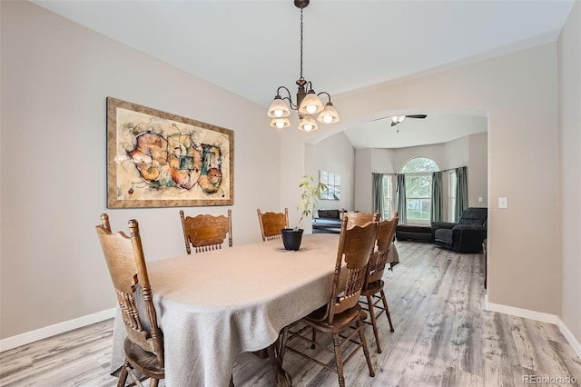 dining space with vaulted ceiling, baseboards, a chandelier, and wood finished floors