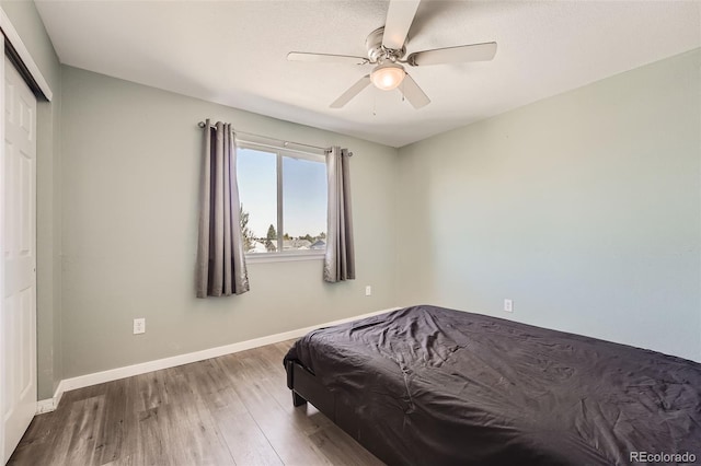 bedroom featuring a ceiling fan, a closet, baseboards, and wood finished floors