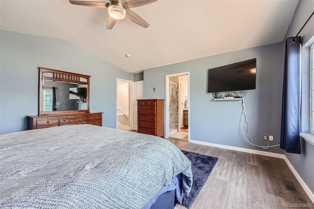 bedroom featuring light wood finished floors, lofted ceiling, visible vents, ensuite bathroom, and baseboards