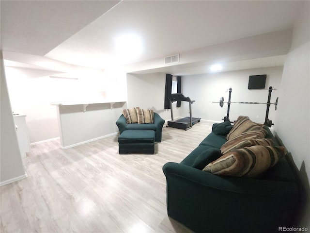 living room with light wood-style flooring, visible vents, and baseboards