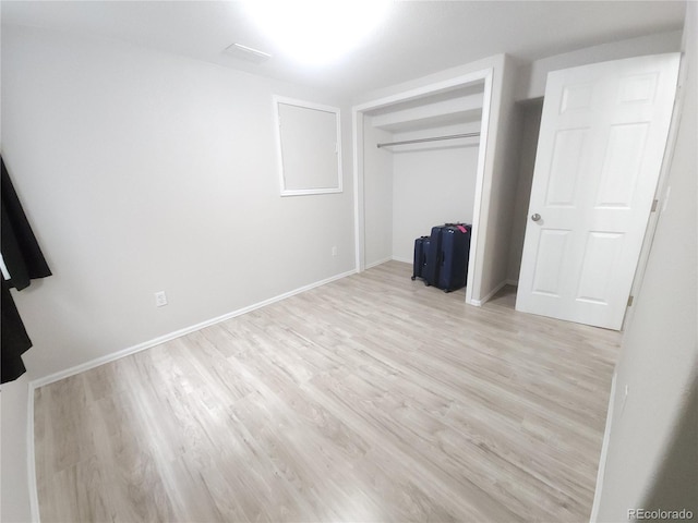 unfurnished bedroom with light wood finished floors, baseboards, and a closet