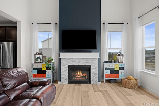 living room with a wealth of natural light, a fireplace, and light hardwood / wood-style floors