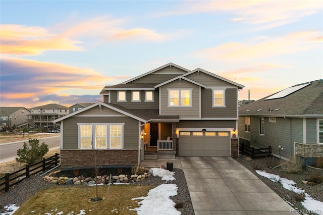 craftsman house featuring concrete driveway, an attached garage, fence, and stone siding