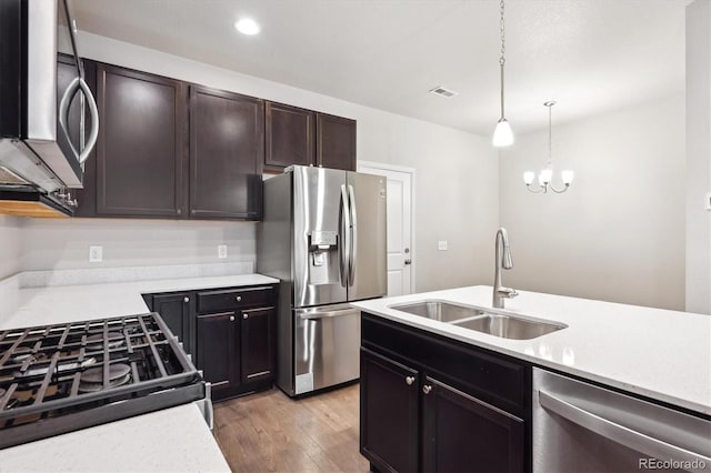 9269 Garnett St Unit C, Arvada, CO 80007 - kitchen with appliances with stainless steel finishes, a sink, light countertops, light wood finished floors, and hanging light fixtures