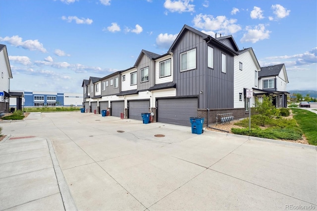 9269 Garnett St Unit C, Arvada, CO 80007 - view of property exterior with board and batten siding, a garage, driveway, and brick siding